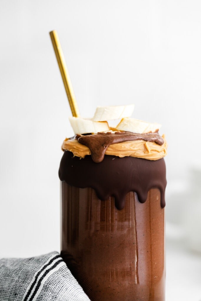 This Chocolate Peanut Butter Banana Smoothie is packed with protein and even has a full serving of greens in it. The best part is, it's healthy and tastes exactly like a peanut butter cup! magic shell on smoothie glass