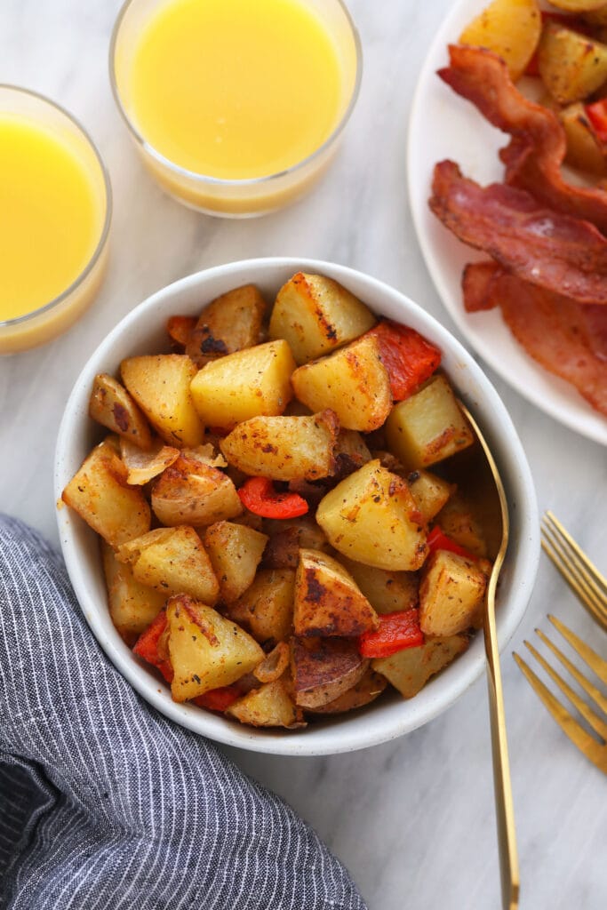 These are the best breakfast potatoes you will ever eat. Perfectly cooked on the inside and crunchy on the outside. Make a big batch of breakfast potatoes and enjoy! breakfast potatoes in a bowl, served next to a glass of orange juice