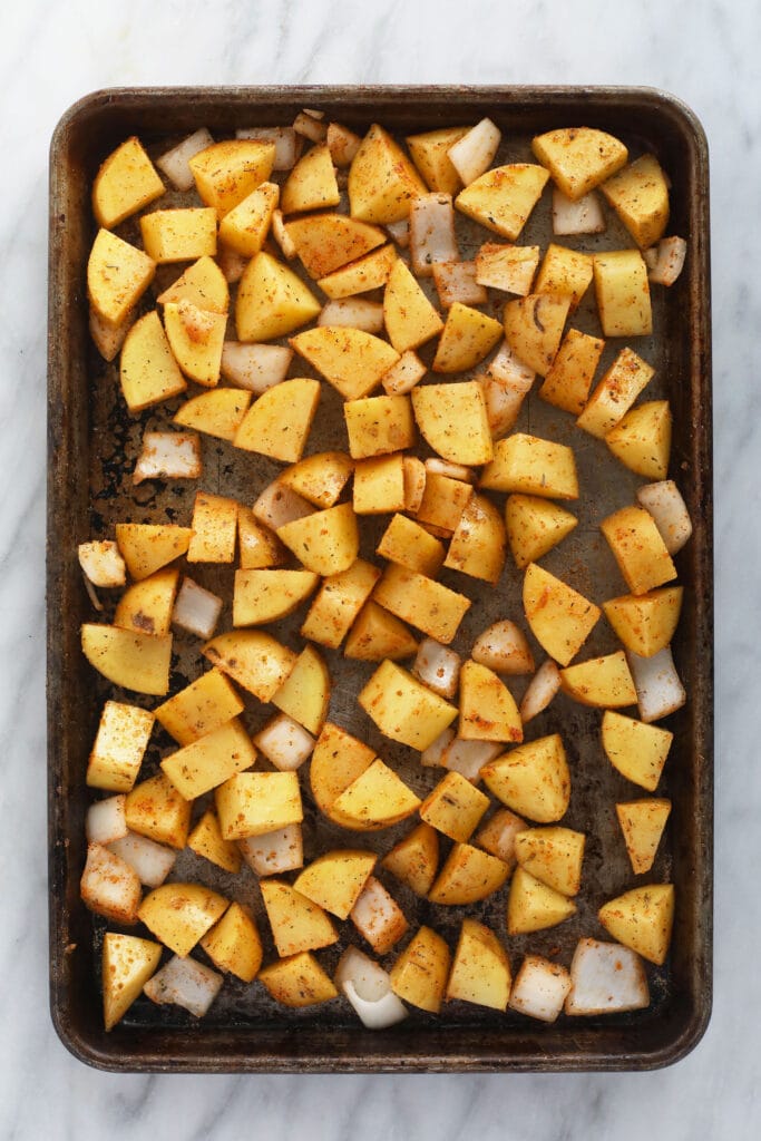 These are the best breakfast potatoes you will ever eat. Perfectly cooked on the inside and crunchy on the outside. Make a big batch of breakfast potatoes and enjoy! sliced breakfast potatoes on a baking sheet, ready to be baked