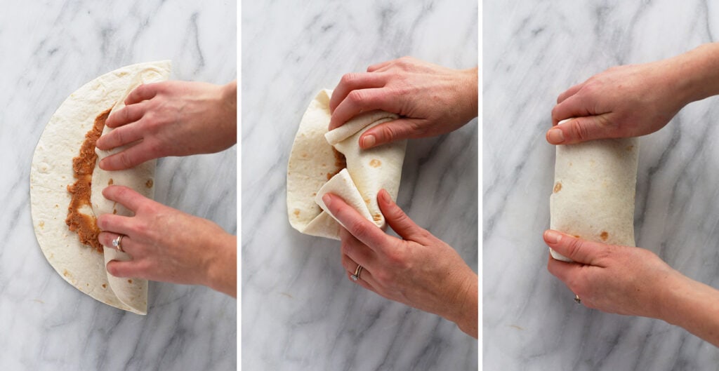 These easy shredded chicken burritos are super flavorful with smothered chicken and fajita veggies, refried beans and Spanish rice. Make a batch and enjoy immediately, or follow our freezer instructions for the ultimate meal prep recipe! shredded chicken burrito being rolled up after all the ingredients have been assembled inside it