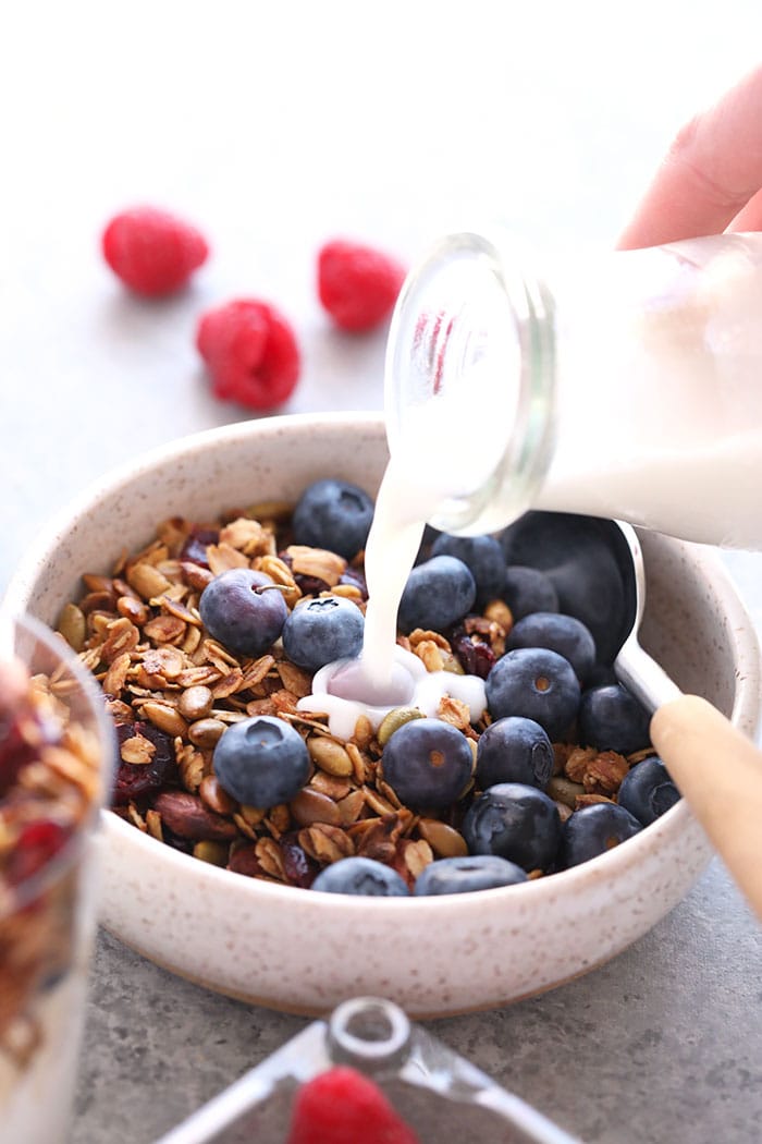A seriously easy homemade granola recipe made with rolled oats, almonds, dried cranberries, and a little maple syrup. Granola in a bowl with milk and blueberries