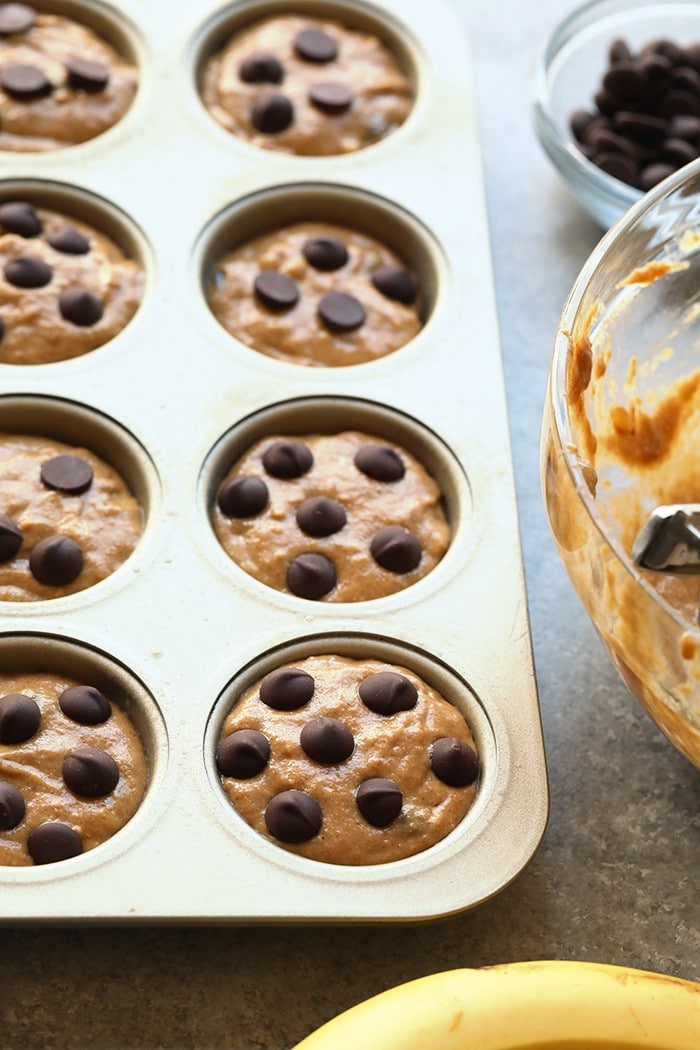 Looking for a healthy banana muffin recipe? This is it! Make a batch of these Healthy Banana Chocolate Chip Muffins for a yummy afternoon pick-me-up all week. banana chocolate chip muffin batter in a muffin tin, ready to be baked