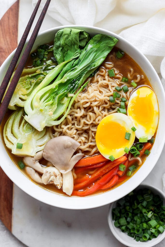 Ramen in a bowl with soft boiled eggs and vegetables.