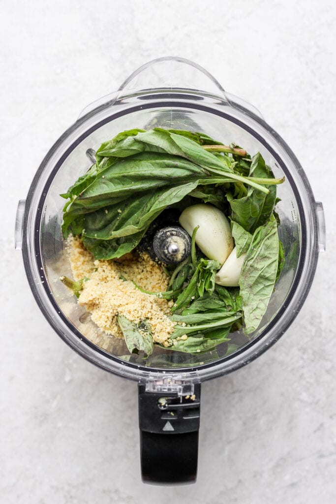 Make this simple vegan pesto recipe with fresh basil, olive oil, lemon juice, and a homemade vegan parmesan cheese. pesto ingredients in food processor