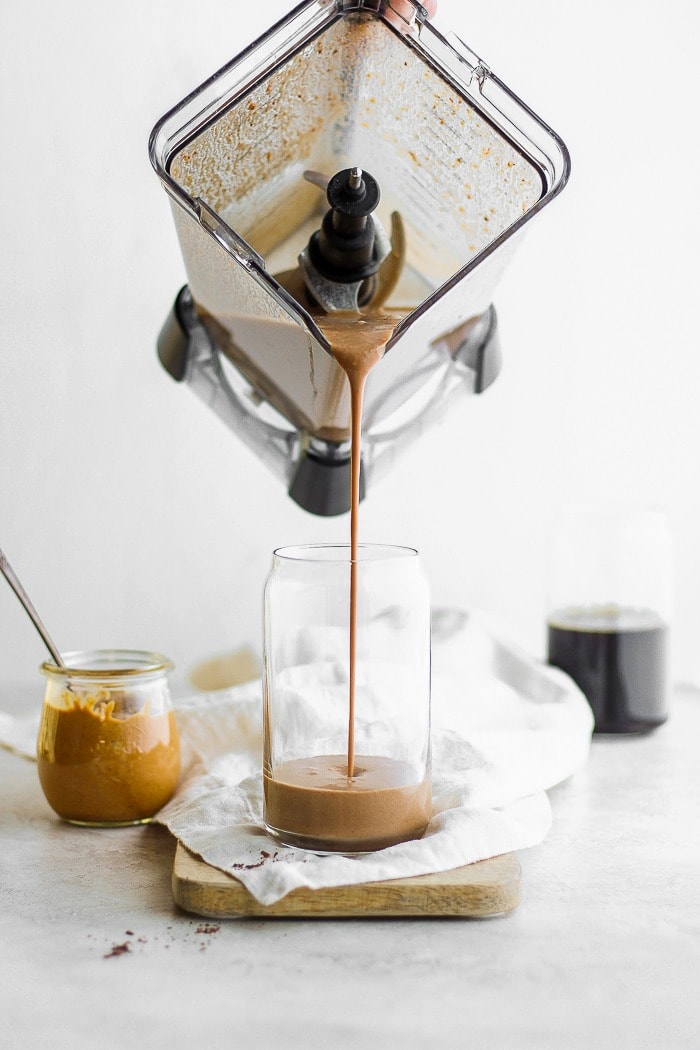 You will absolutely love this coffee protein shake recipe. It's not your average protein shake because it's made with cold brew coffee, peanut butter, and banana - the ultimate flavor combo! A protein smoothie being poured into a glass