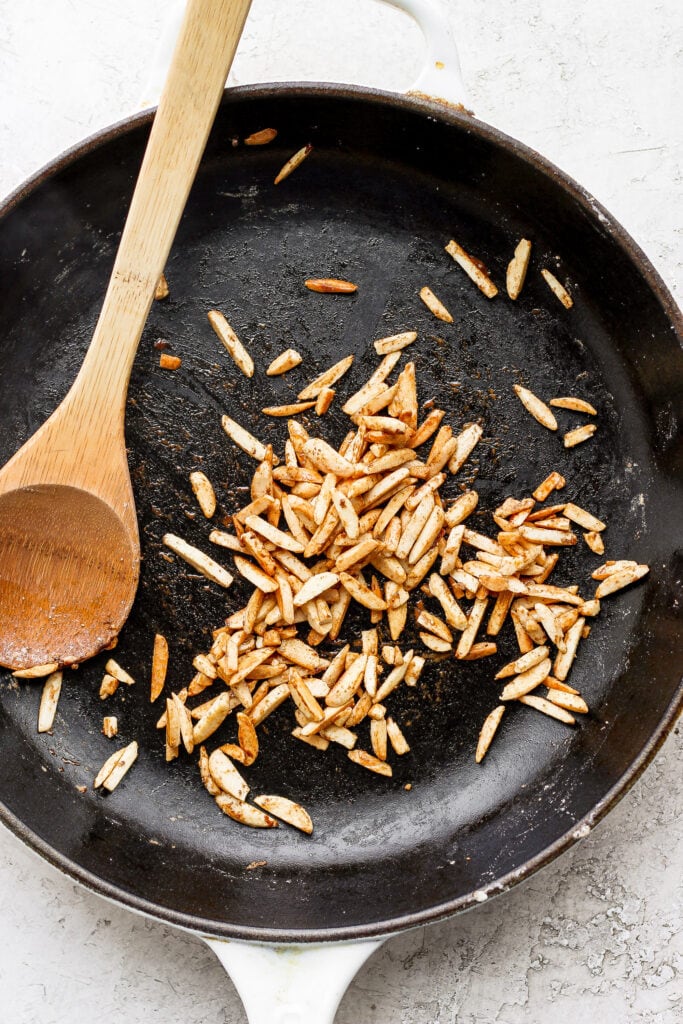 Slivered almonds toasting in a pan.