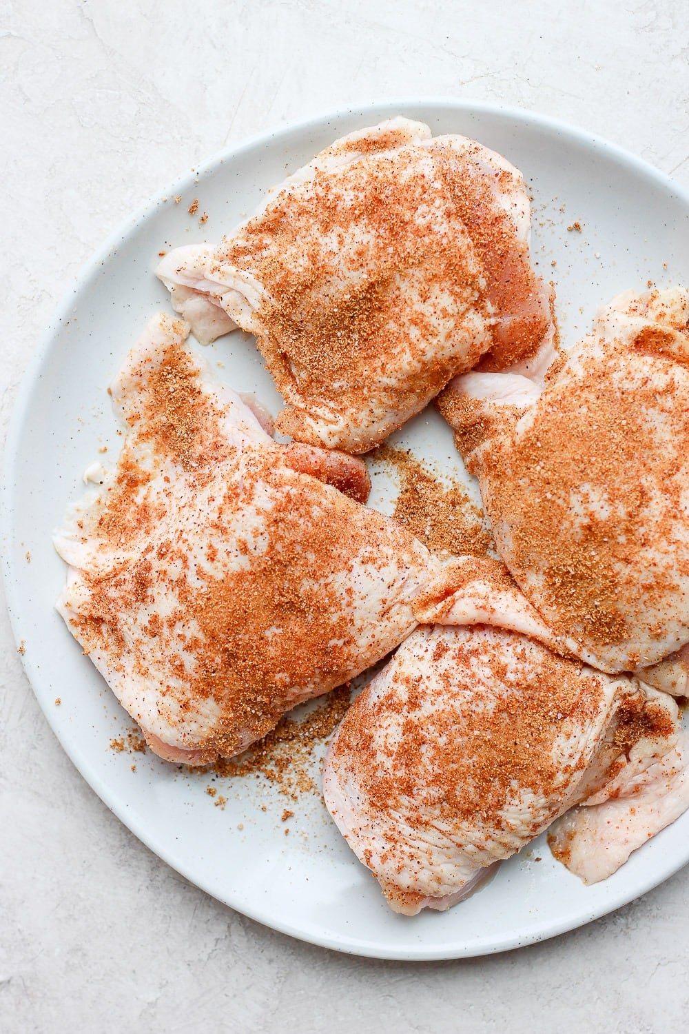 These are the best grilled chicken thighs because the skin gets nice and crispy on the outside while the inside is tender and juicy. uncooked chicken thighs on plate