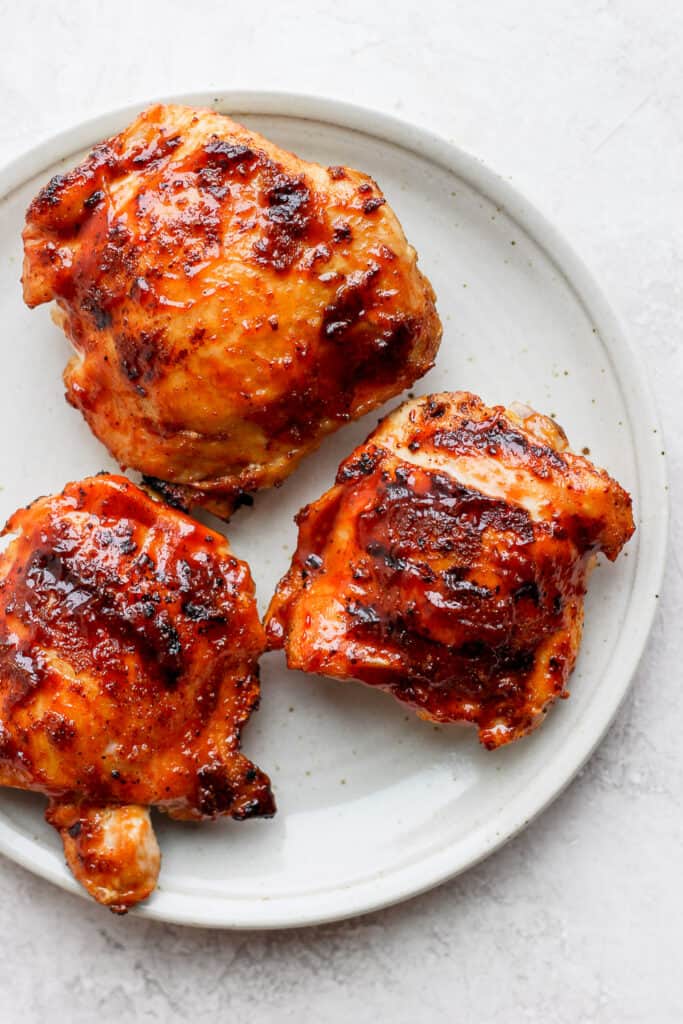 These are the best grilled chicken thighs because the skin gets nice and crispy on the outside while the inside is tender and juicy. 3 grilled chicken thighs on plate