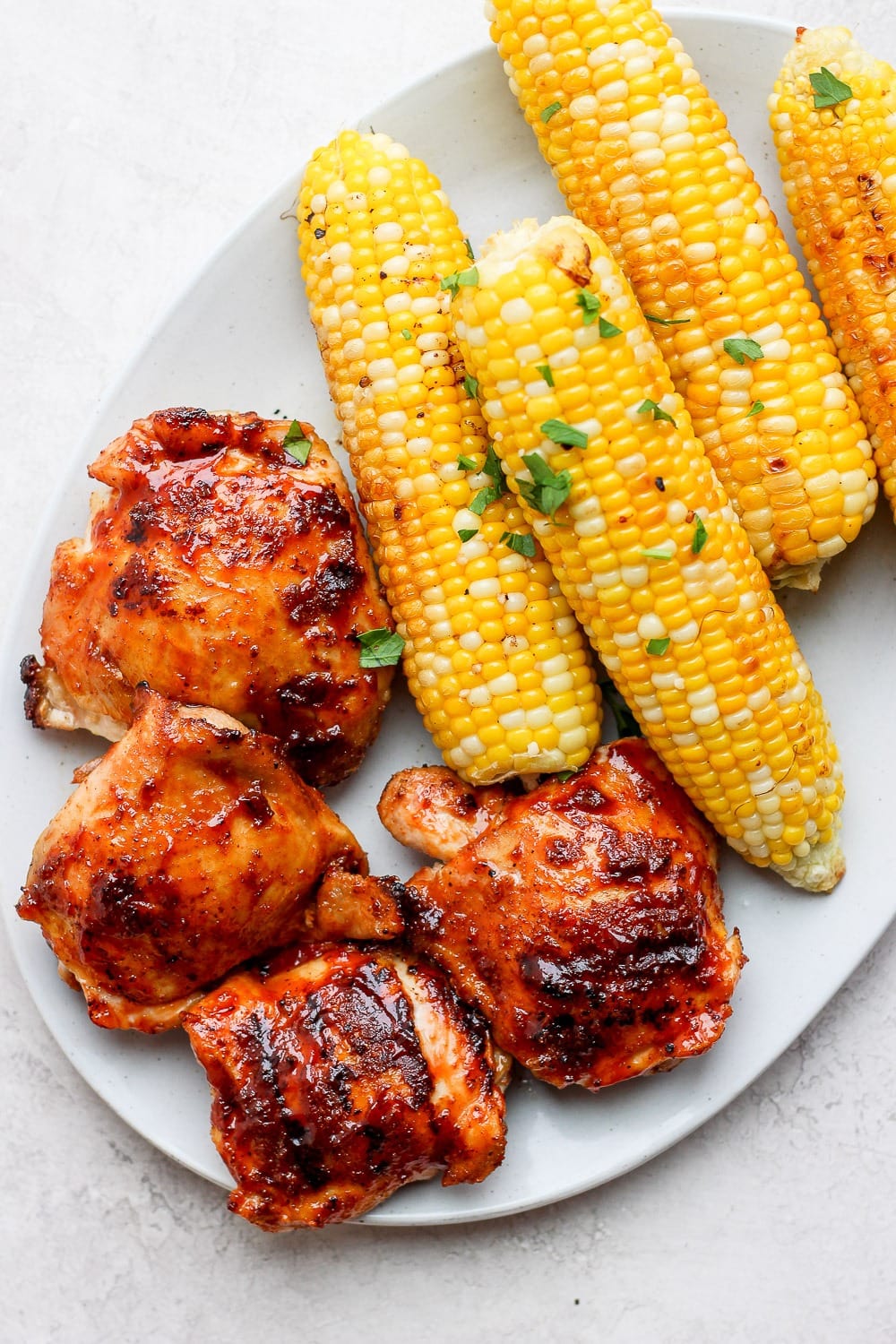 One of our favorite grilled chicken thigh recipes are this incredibly juicy bbq grilled chicken thighs made with a dry rub and your favorite bbq sauce! grilled chicken thighs with corn on plate