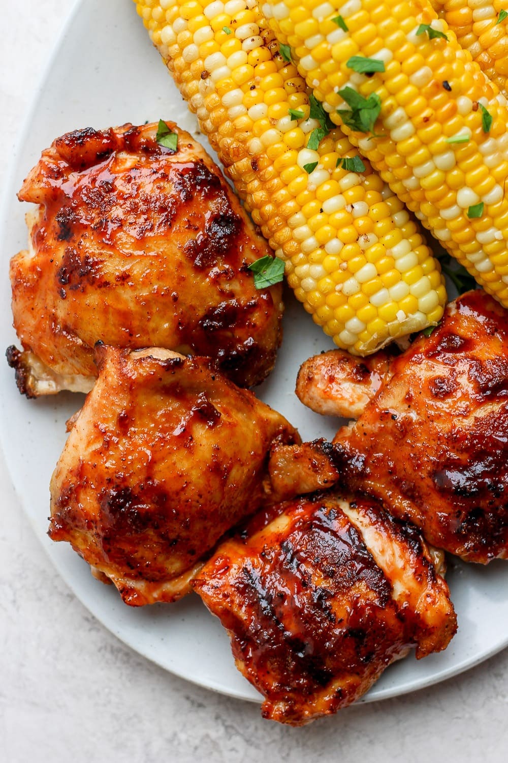 One of our favorite grilled chicken thigh recipes are this incredibly juicy bbq grilled chicken thighs made with a dry rub and your favorite bbq sauce! chicken thighs with corn cob on plate