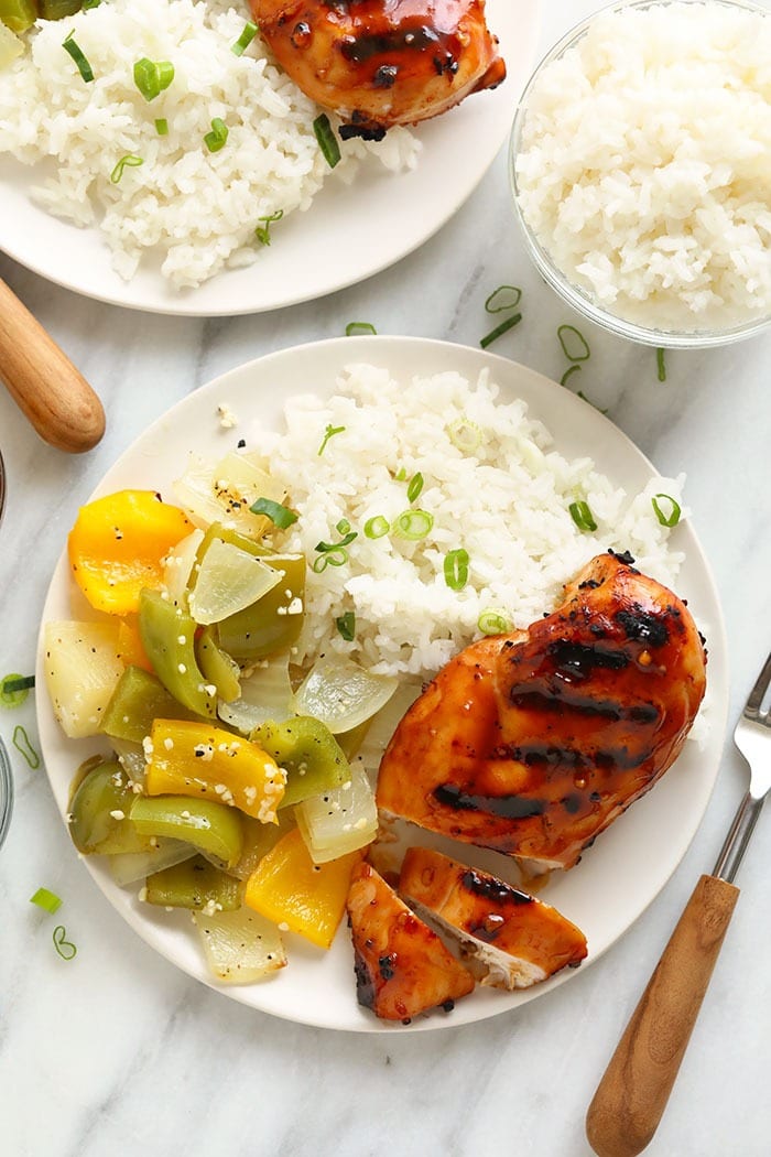 Turn on that grill and prepare this grilled teriyaki chicken for dinner tonight! People always wonder how to make chicken teriyaki that tastes like their favorite take-out recipe and we have figured it out! This healthy grilled teriyaki chicken recipe is a healthier version of your favorite take-out and makes a perfect chicken meal prep meal for the week. Make it today! Grilled chicken breast on a plate with rice and vegetables