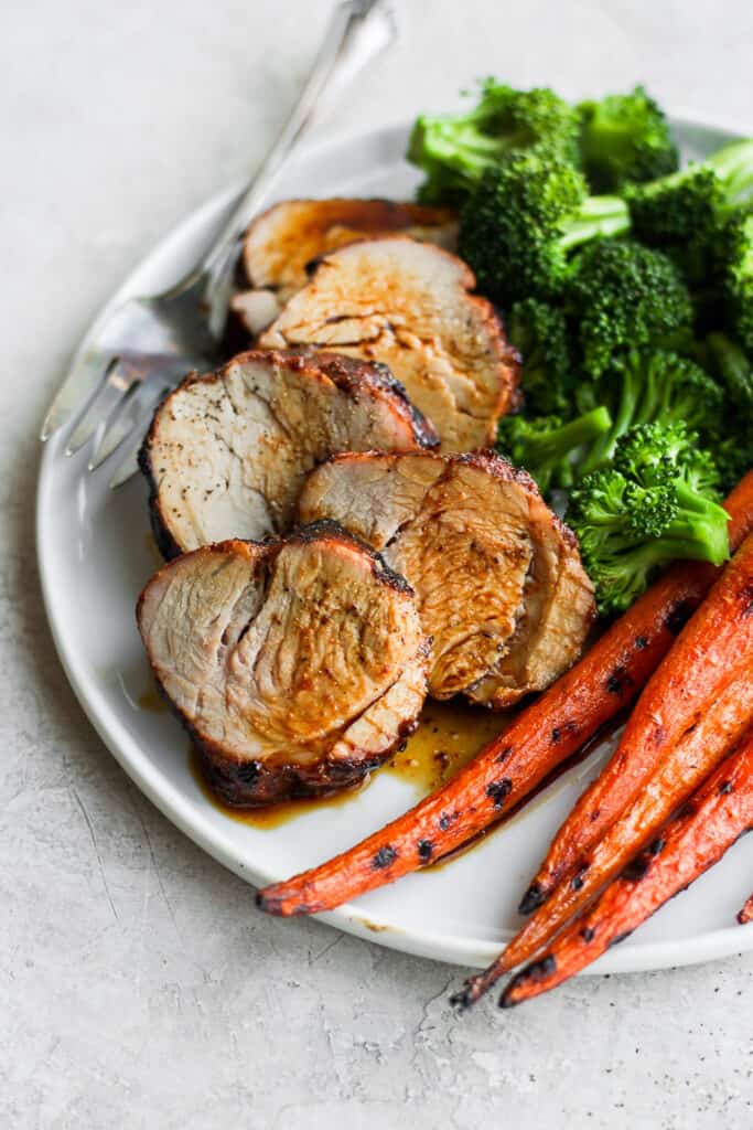 The easiest, most flavorful pork tenderloin marinade you'll ever try. This pork tenderloin marinade recipe is sweet and salty made with BBQ sauce, soy sauce, and garlic. juicy sliced pork on a plate