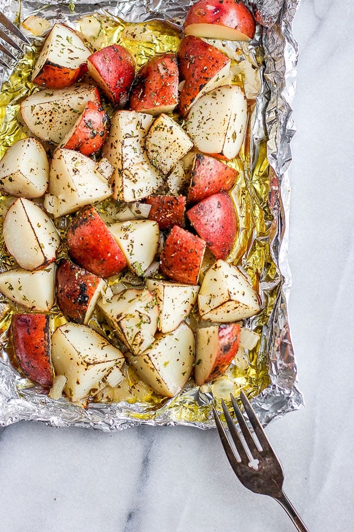Make our crispy grilled red potatoes recipe for an easy summer side made on the grill! red potatoes on tin foil covered in olive oil and spices