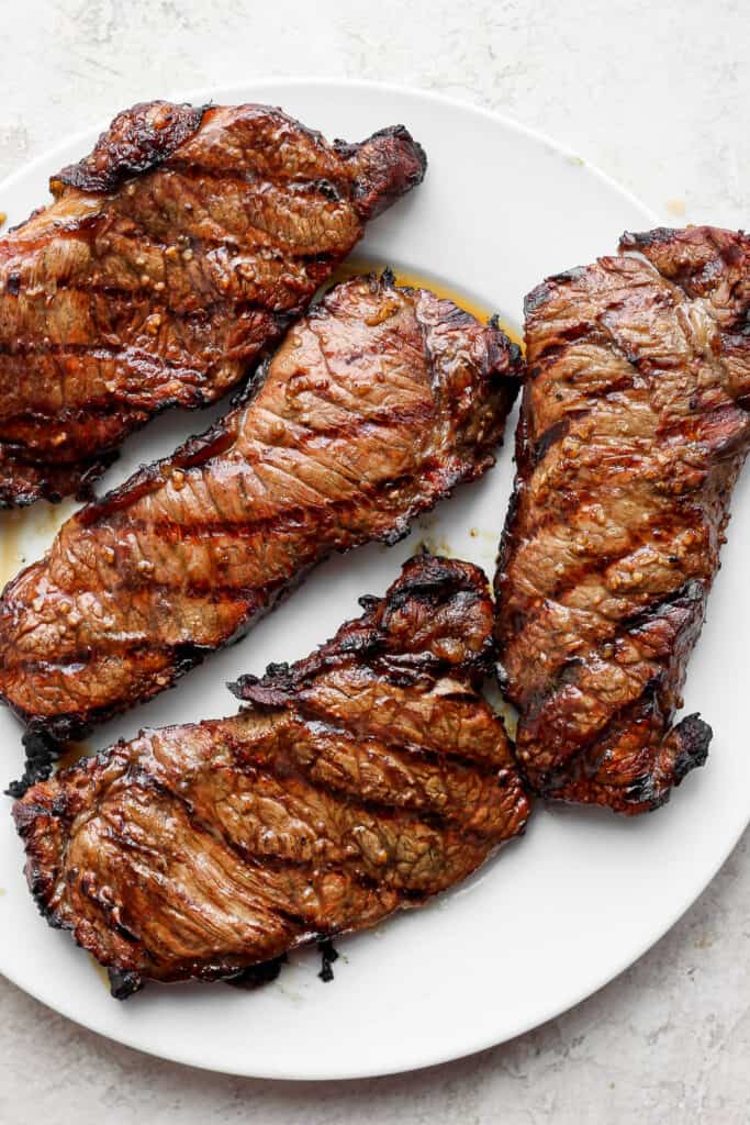 Grilling steak may seem intimidating, but in this post, we'll teach you how to grill steak and make it perfectly juicy on the inside with a beautifully charred crust on the outside every time. 4 large grilled steaks on a plate