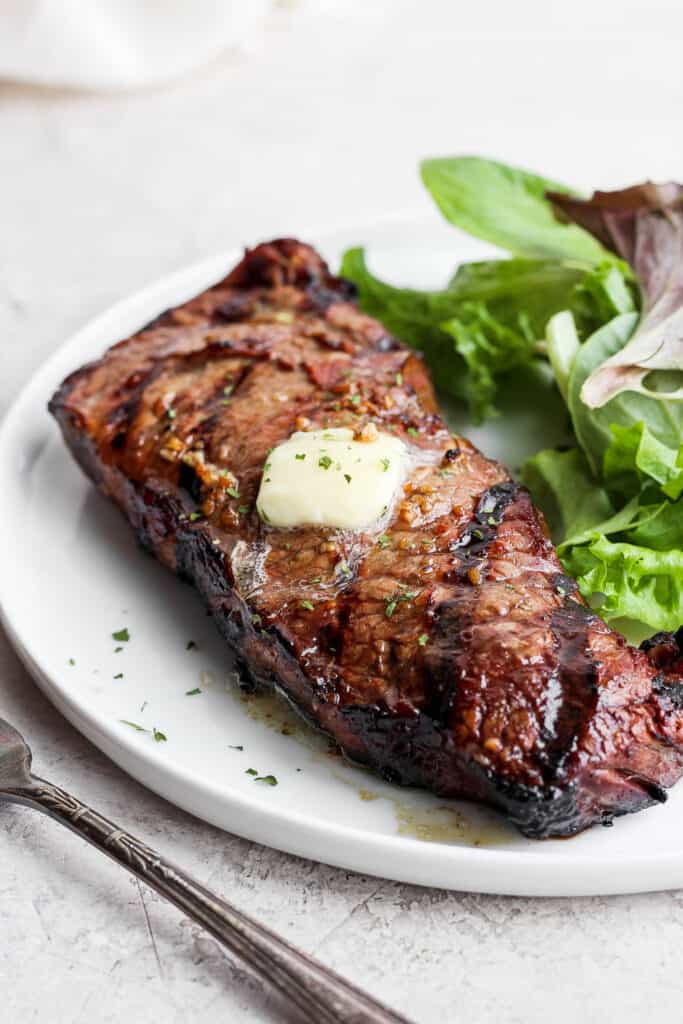 Grilling steak may seem intimidating, but in this post, we'll teach you how to grill steak and make it perfectly juicy on the inside with a beautifully charred crust on the outside every time. steak on a plate with greens