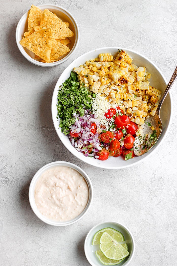 Take dinner up a notch and add this Mexican Street Corn Salad to the menu! This delicious healthy side dish is made with grilled corn, fresh veggies, and the most delicious cotija yogurt sauce. Drop everything you're doing and make this Mexican Street Corn Salad today! Mexican Street Corn Salad in a bowl