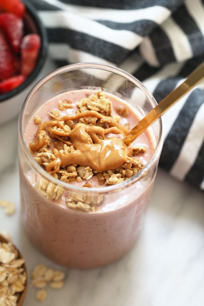 Start your day off right with this protein-packed healthy breakfast smoothie. Filled with fruit, oats, protein powder, almond milk and a little hit of peanut butter, this breakfast smoothie of all breakfast smoothies will keep you feeling satisfied til lunch. healthy breakfast smoothie in glass drizzled with peanut butter