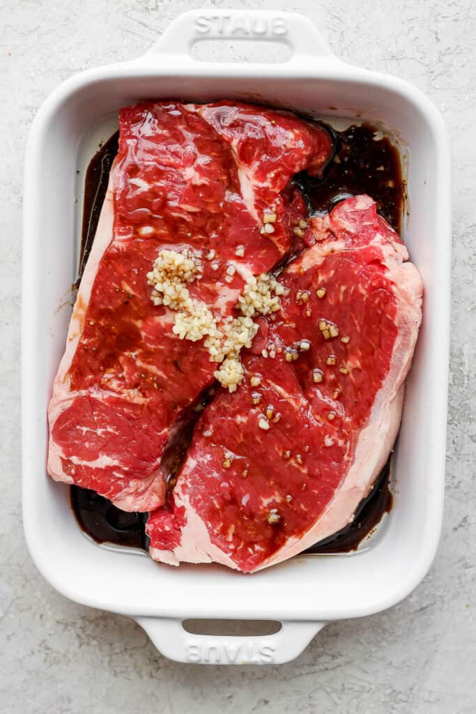 steaks marinating in baking dish