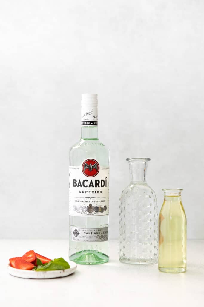 Get fancy with your white rum cocktails and make this strawberry mojito recipe! It's made with strawberries, mint, white rum, club soda, and a homemade mint simple syrup. cocktail ingredients on countertop