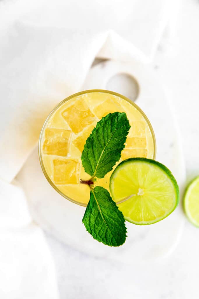 A refreshing virgin margarita recipe that's made with lime juice, orange juice, a little agave nectar, and sparkling water. glass full of margarita and a lime wedge