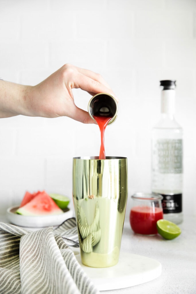 Pouring watermelon juice into a cocktail shaker.