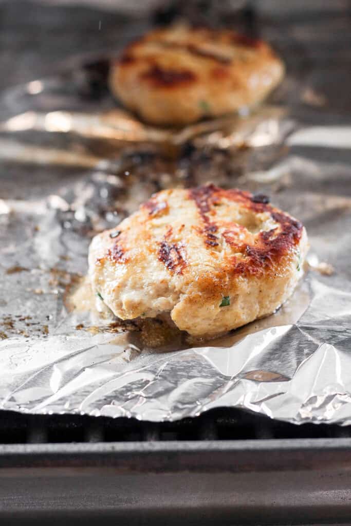 If you are looking for a staple chicken burger recipe, this is it! These ground chicken burgers are so flavorful and moist and topped with our secret burger sauce. ground chicken burger on tin foil on grill