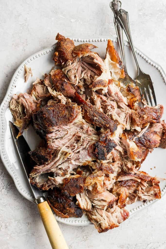 This incredible slow roasted pork shoulder has a yummy, crunchy crust on the outside and tender sweet and smokey meat on the inside. shredded pork on platter