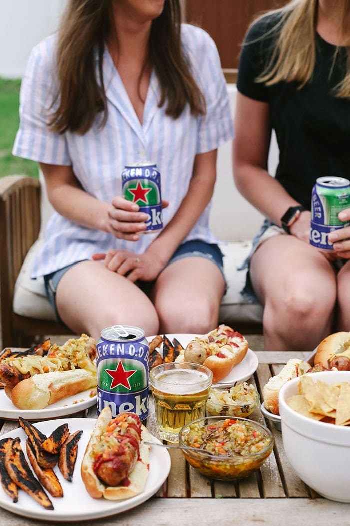 Ever heard of beer brats? Beer boiled brats are by far the most delicious way to cook brats. Start by boiling your brats in beer and then finish them off with a sear on the grill, some ketchup & mustard, and relish too! 2 girls eating beer brats and drinking beers