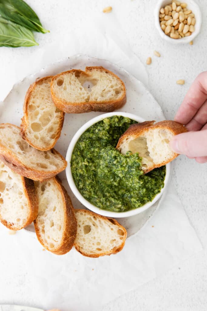 This basil pesto is made with simple ingredients of fresh basil, parmesan cheese, garlic, lemon juice, and olive oil. This pesto recipe is perfect for bread dipping and delicious tossed with pasta. pesto in bowl with bread