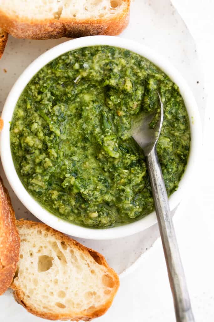 This basil pesto is made with simple ingredients of fresh basil, parmesan cheese, garlic, lemon juice, and olive oil. This pesto recipe is perfect for bread dipping and delicious tossed with pasta. pesto with spoon in bowl