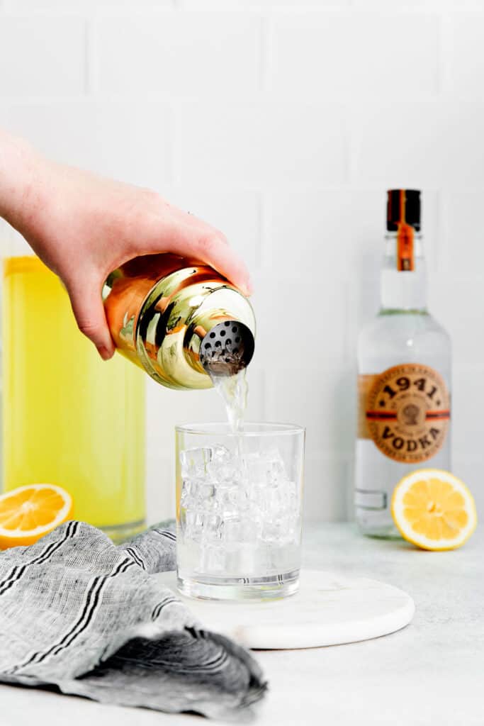 Vodka lemonade is the perfect easy cocktail to make any time of year. It's made with minimal ingredients and the perfect combo of sweet and sour. pouring vodka lemonade into glass