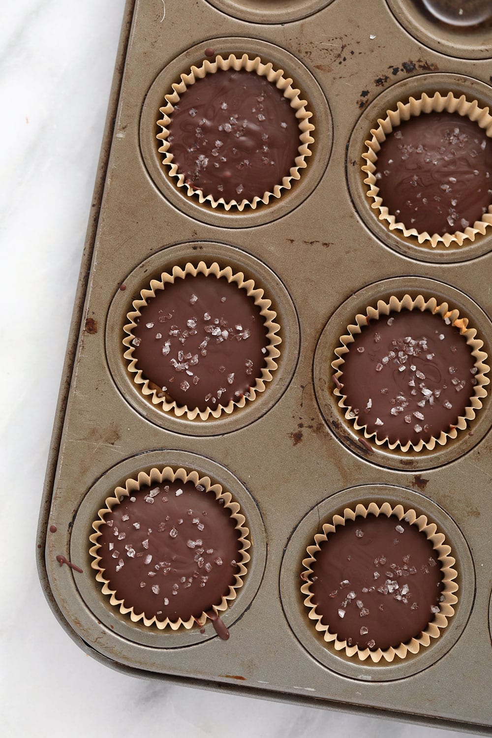 Homemade almond butter cups are a simple dessert that will satisfy your sweet tooth craving! Plus, these almond butter cups are topped with flakey sea salt. almond butter cups in muffin tin