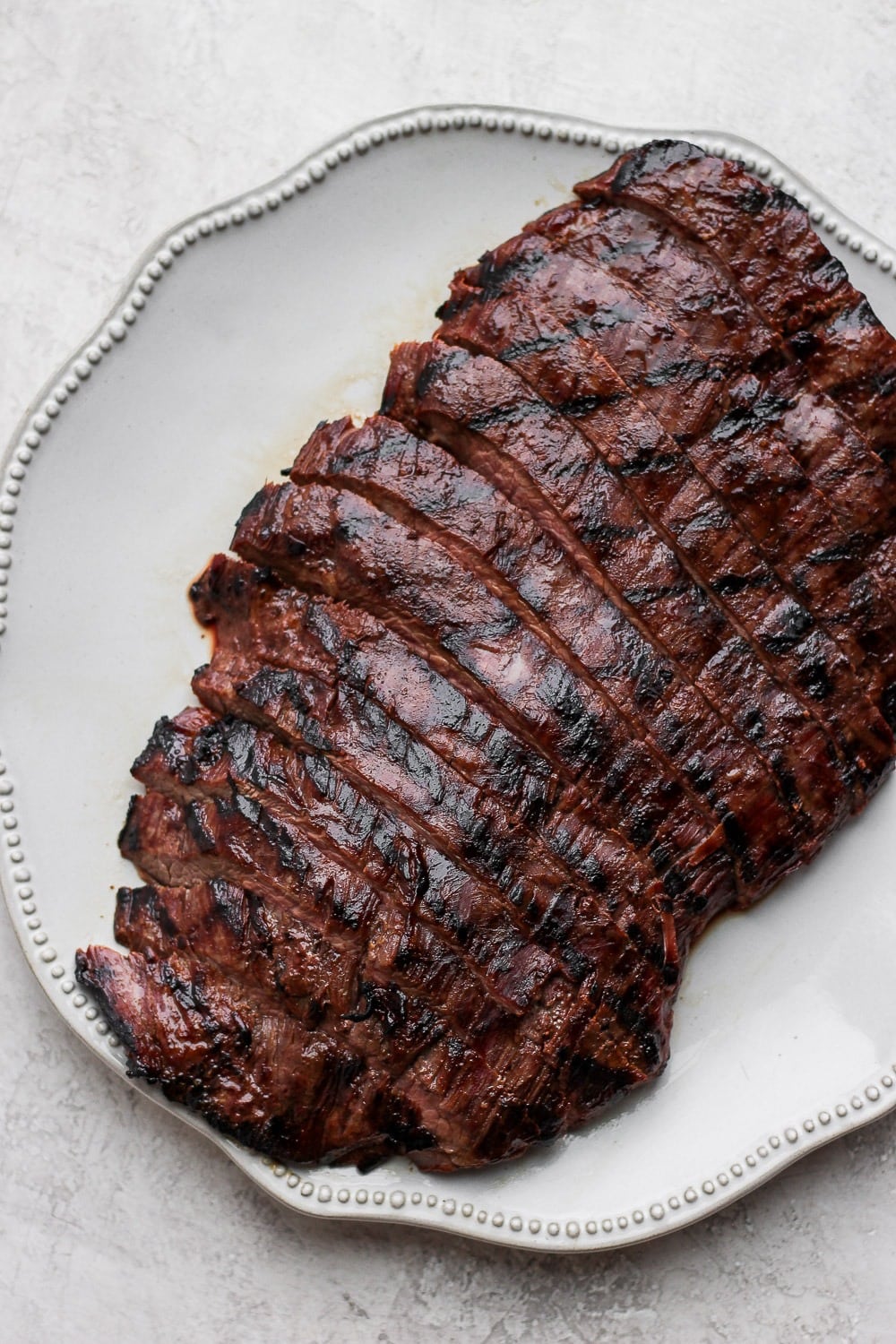 Flank steak is best served in thin strips! Cut against the grain of the meat and you will have perfect, tender strips for dinner! Grilled flank steak on a plate that is cut into strips!