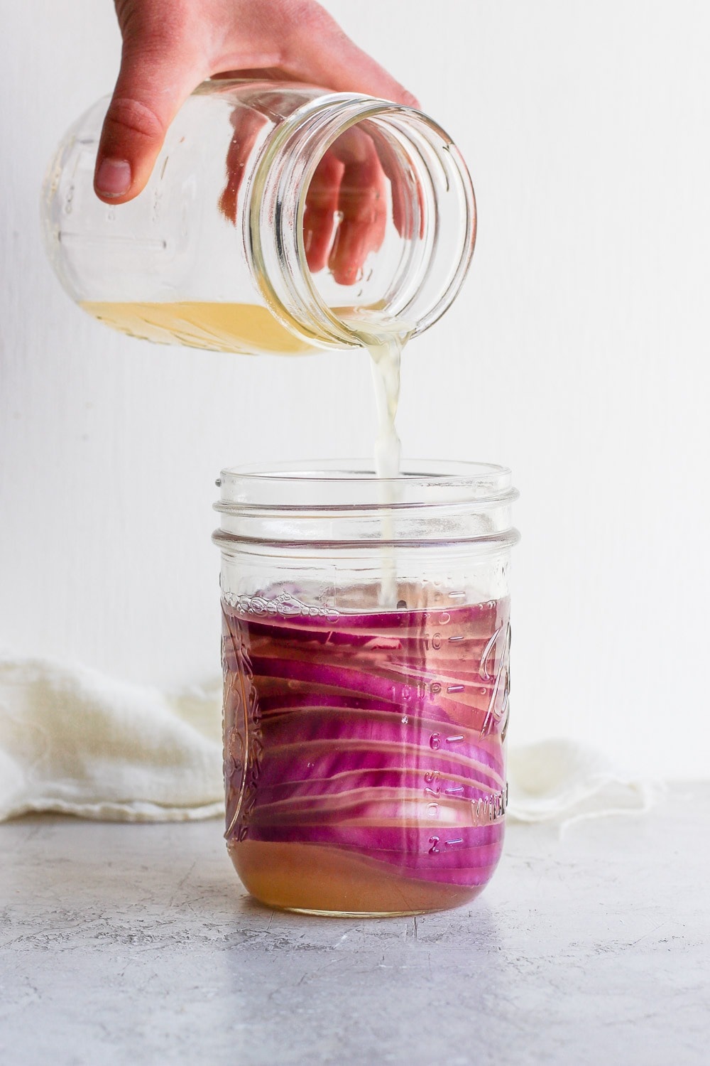 These quick pickled onions are a dream! Toss red onion with apple cider vinegar, white vinegar, a little sugar and salt. Throw them in the fridge and 2 hours later you've got pickled onions for dinner and the week ahead! Pouring Vinegar into the mason jar with onions