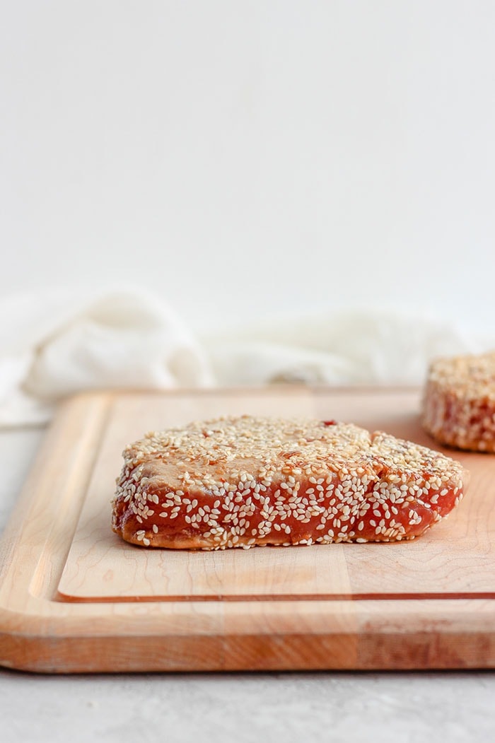 Perfectly Seared Ahi Tuna every single time! This how-to sear ahi tuna recipe is seasoned with delicious Asian flavors and packs 46g of protein per serving. Make this for dinner tonight! seared ahi tuna on a cutting board