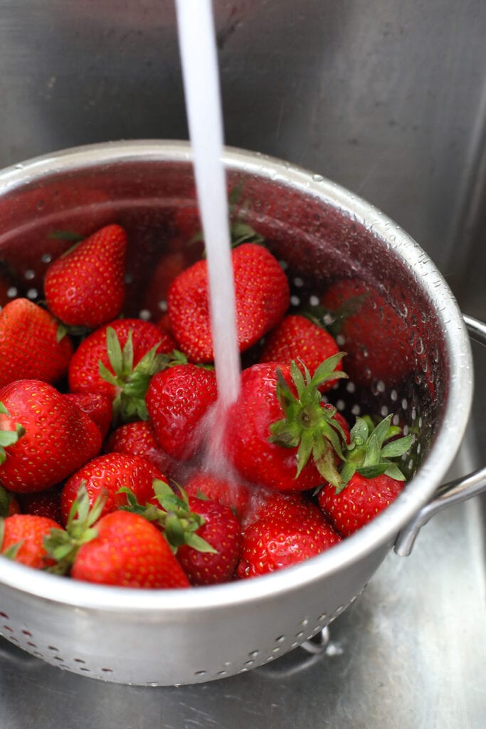 Rinsing fresh strawberries with water.