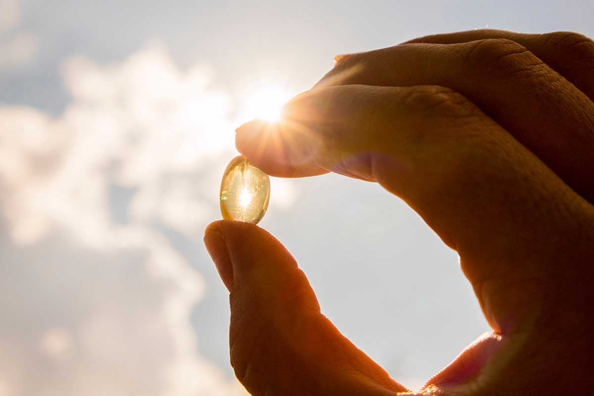 Woman holding up a vitamin to the sun
